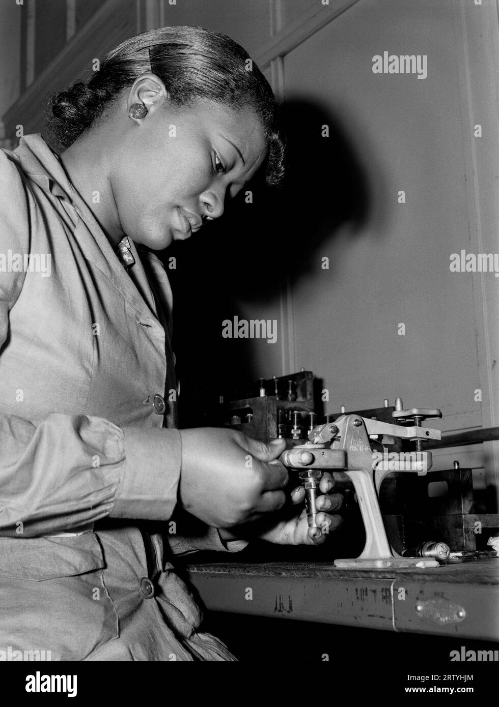 Melrose Park, Illinois Juli 1942 nur zwei Monate vor der Arbeit konditionierte Mighnon Gunn gebrauchte Zündkerzen für die Wiederverwendung bei der Prüfung von Flugzeugmotoren im Buick-Werk in Melrose Park, IL. Viele Frauen traten zum ersten Mal während des Zweiten Weltkriegs in die Belegschaft ein und übernahmen Fabrikjobs, die normalerweise von den Männern, die jetzt im Krieg kämpften, gearbeitet wurden. Foto von Ann Rosener für die Farm Security Administration. Stockfoto