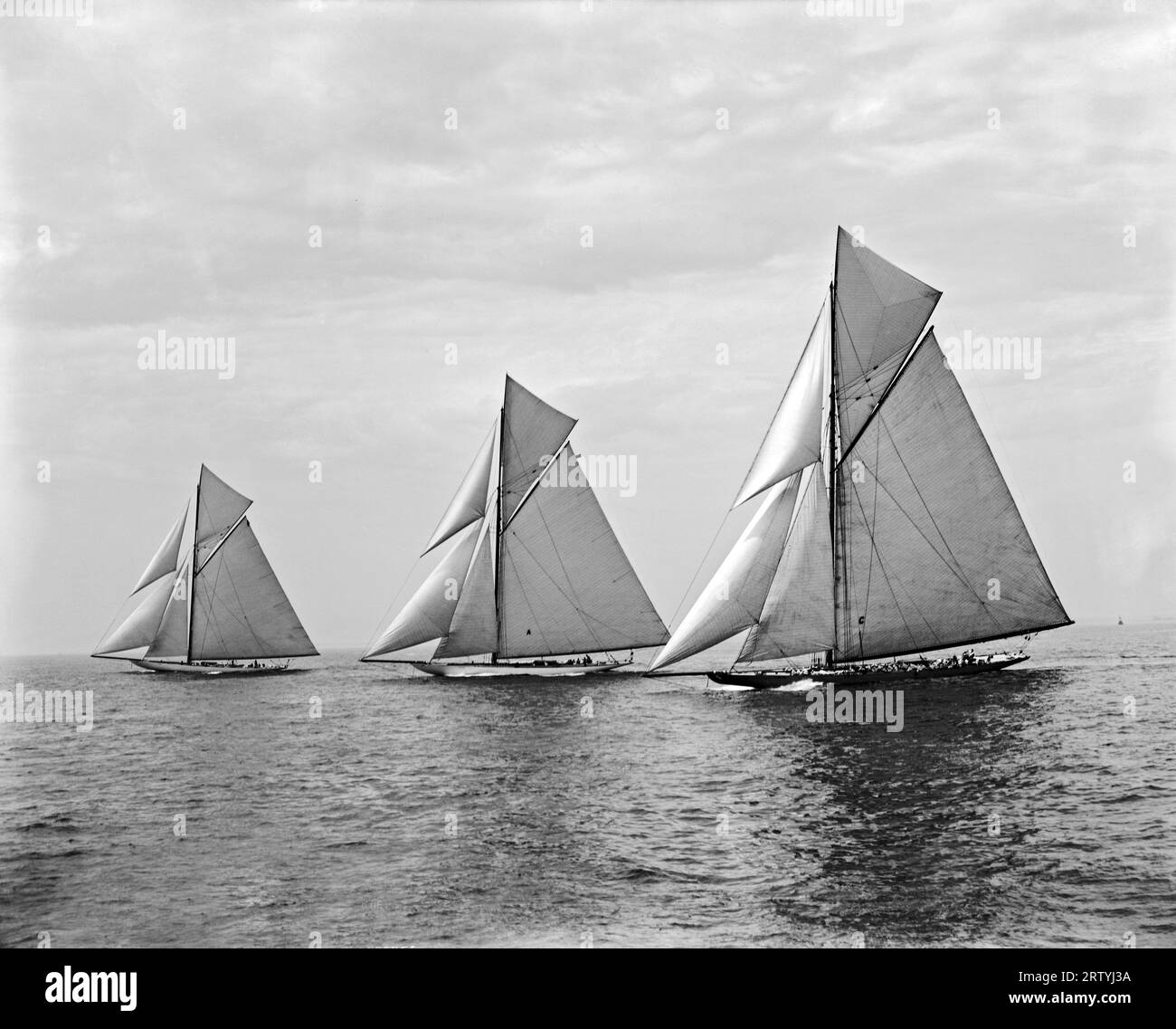 New York, New York 1901 beim Start der America’s Cup-Rennen 1901 sind die „Constitution“ (eine Schlinge), „Independence“ (eine Yacht) und „Columbia“ (eine Schlinge) Hals in Hals. „Columbia“ gewann schließlich 1901 das zweite Jahr in Folge die America’s Cup-Rennen und stellte damit einen neuen Rekord für die Anzahl der aufeinanderfolgenden Siege auf. Stockfoto