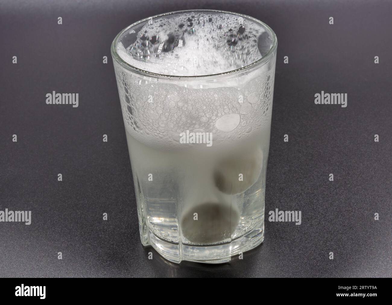Auflösen von Brausetabletten in einem Glas mit Wassernaht auf Schwarz Stockfoto