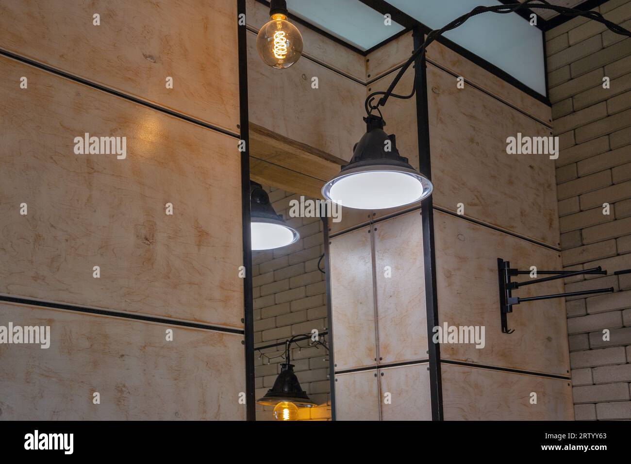 Elektrische Loftlampen im minimalistischen Industriestil gegen Spiegel im Innenbereich Stockfoto