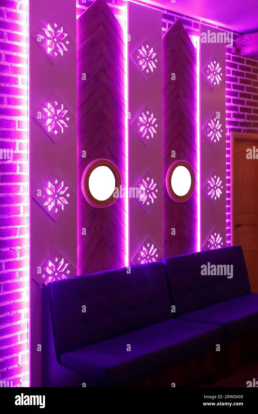 Dekoratives Innendesign mit Ziegelwand, Spiegeln, Sofa und Neonpink-Licht. Stockfoto