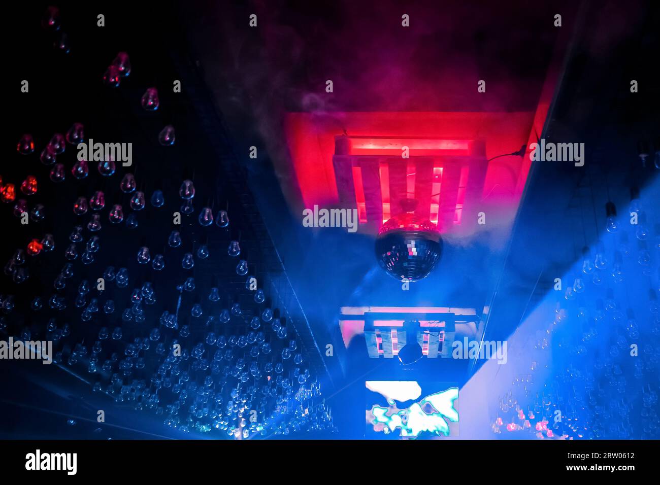 Ein Element der modernen Inneneinrichtung eines Nachtclubs, eine Decke mit Glühbirnen in Neonlicht und eine Discokugel. Stockfoto