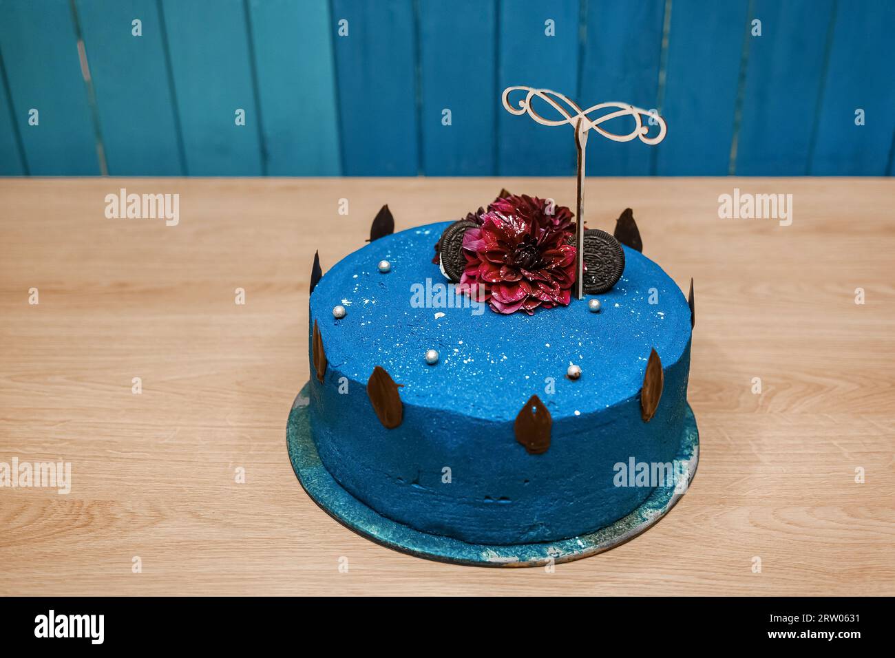 Festlicher süßer köstlicher Kuchen mit dekorativem Geburtstagsgeschenk in Blaucremefarben steht auf einem Holztisch. Stockfoto