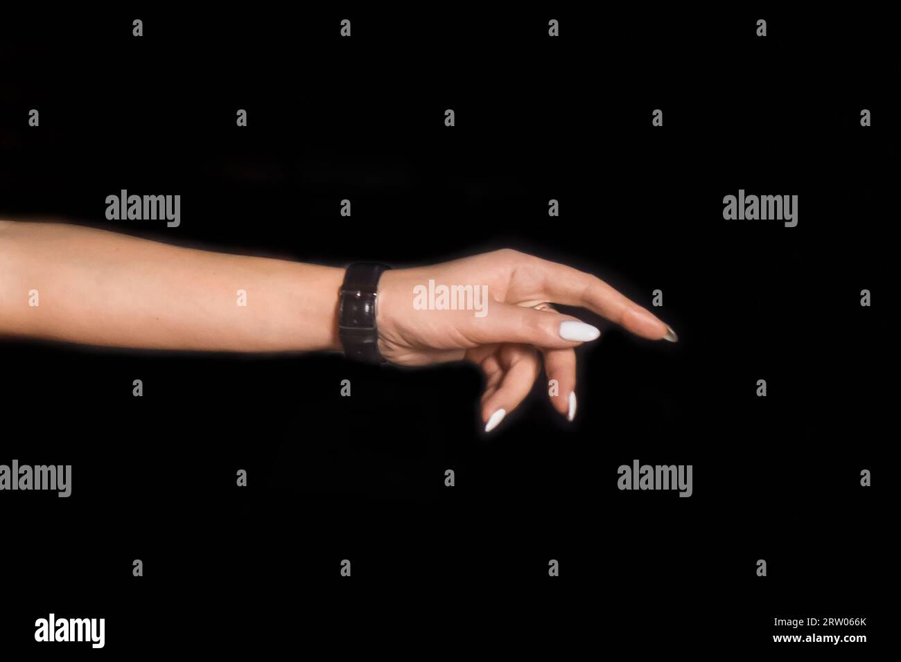 Eine ausgestreckte Frauenhand drückt die Hände des Mädchens mit den Fingern gegen den schwarzen Hintergrund. Stockfoto