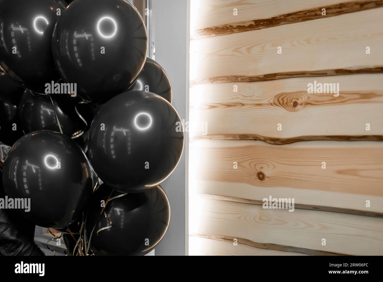 Schwarze stilvolle Helium-Luftballons für ein modernes Weihnachtsfest auf hölzernem Hintergrund. Stockfoto
