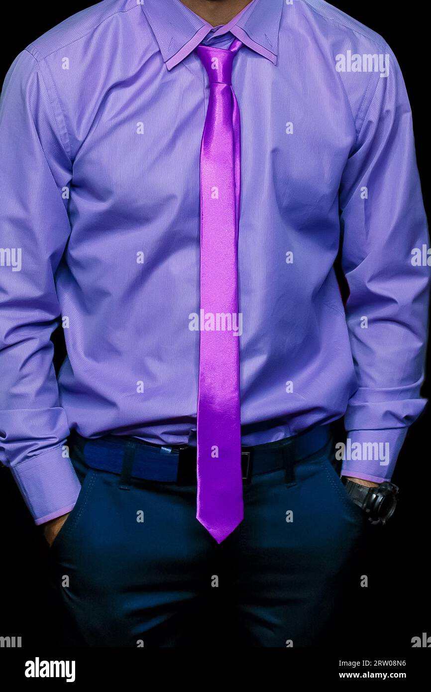 Herren Mode Mode Business man Look Hände in Taschen lila Hemd und rosa Krawatte Nahaufnahme auf schwarzem Hintergrund, weicher Fokus. Stockfoto
