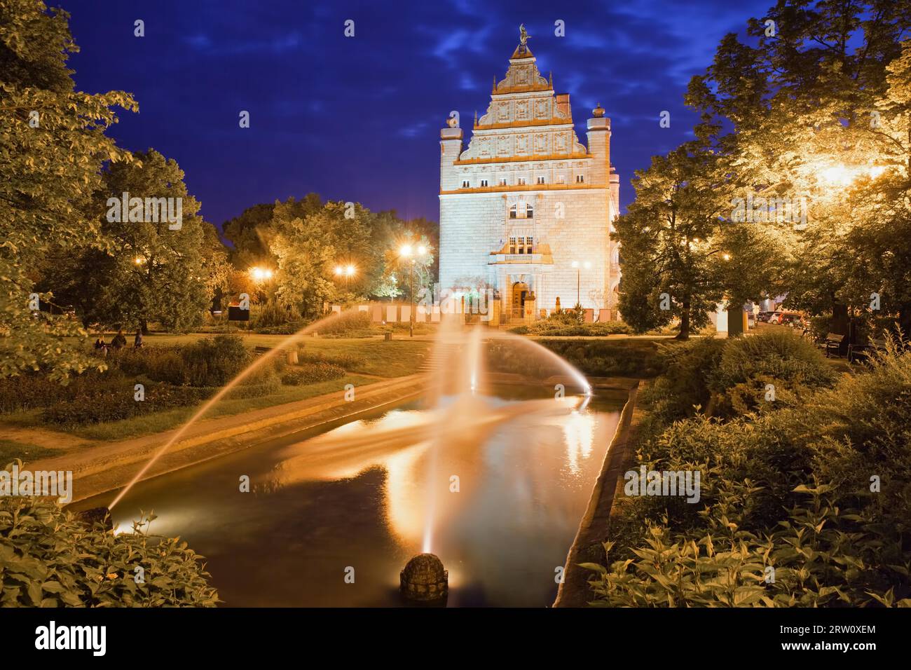 Park mit Brunnen bei Nacht in Torun, Polen und Collegium Maximum der Nicolaus Copernicus Universität Stockfoto