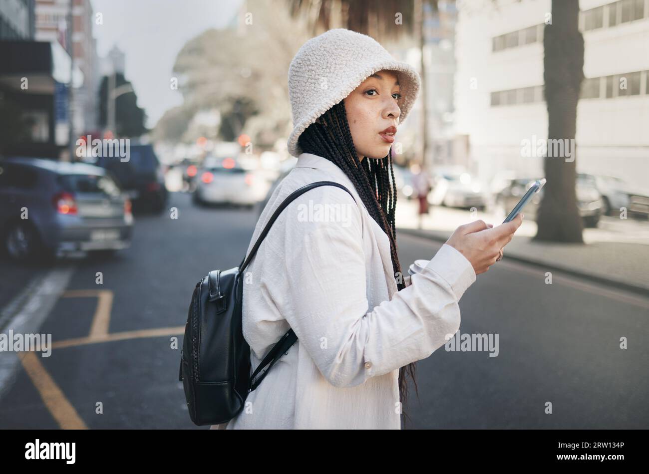Frau auf der Straße mit Telefon, Taxi-App und Reiseurlaub mit Streetwear, Warten und Online-Standort. Influencer, Blogger oder Gen z Girl mit URBAN Stockfoto