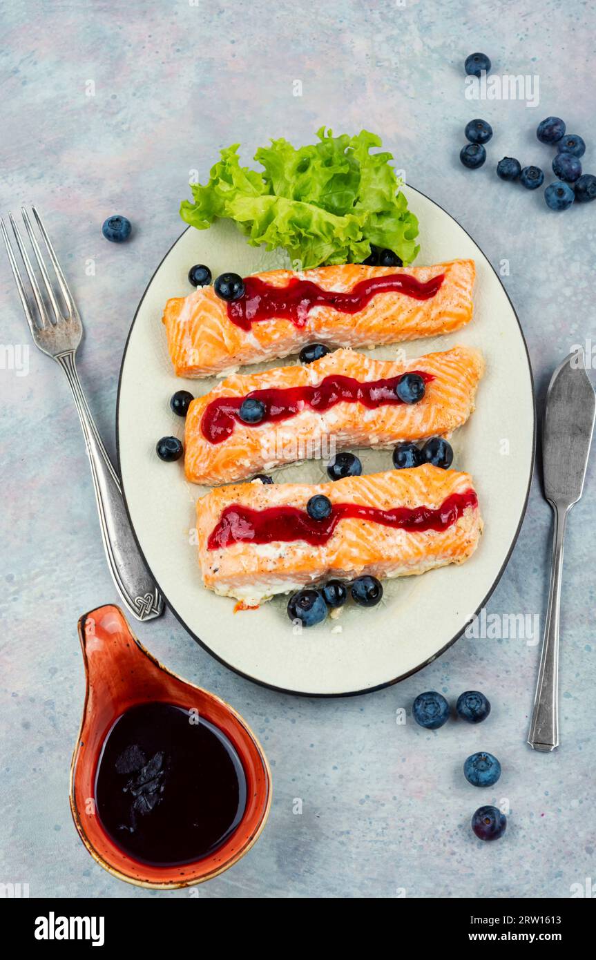 Geröstetes Lachsfilet mit Heidelbeersauce auf Keramikplatte. Stockfoto