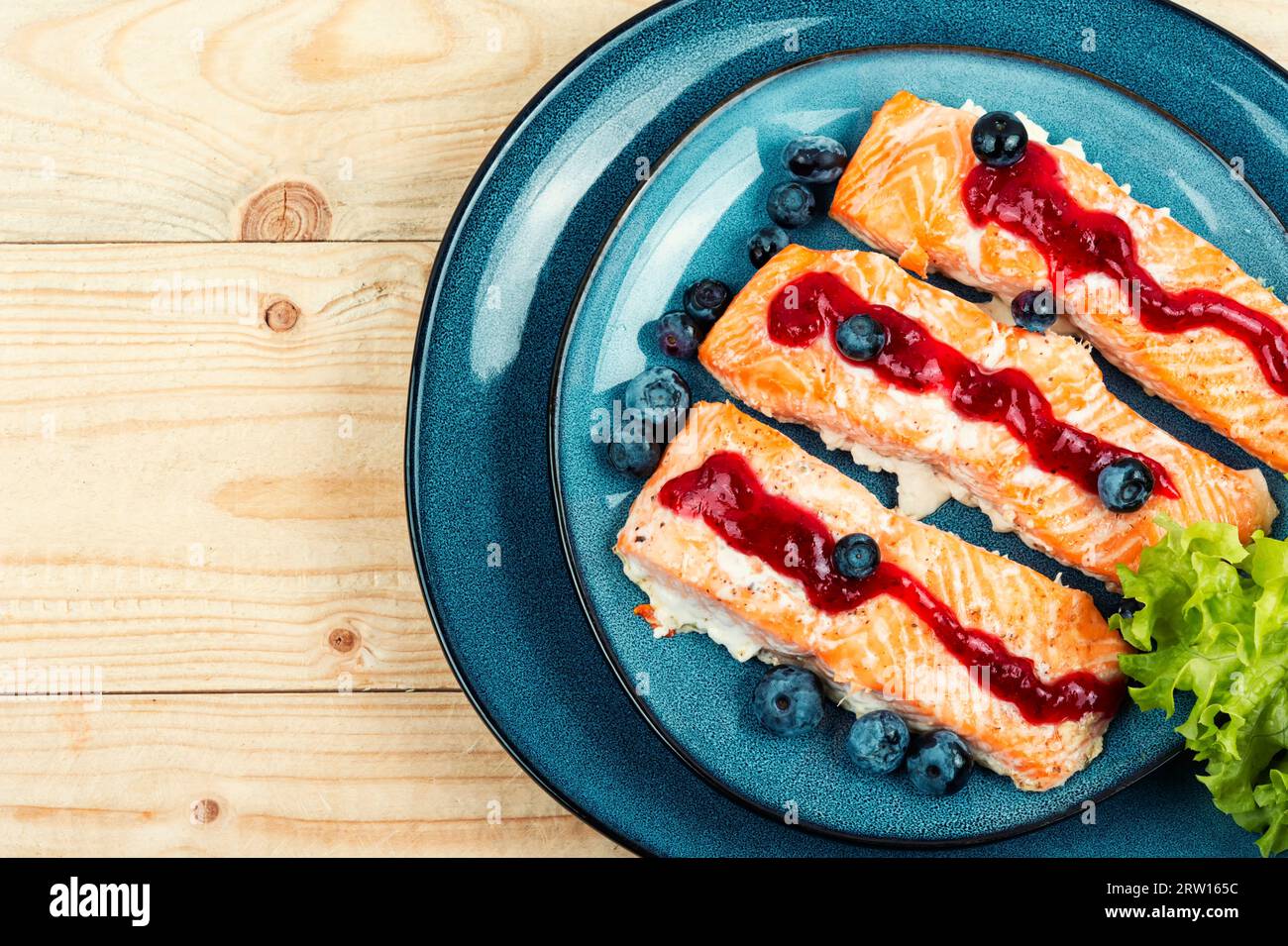 Geröstetes Lachsfilet mit Heidelbeer-Sauceon auf einem rustikalen Holztisch, Keto-Diät. Leerzeichen für Text. Stockfoto