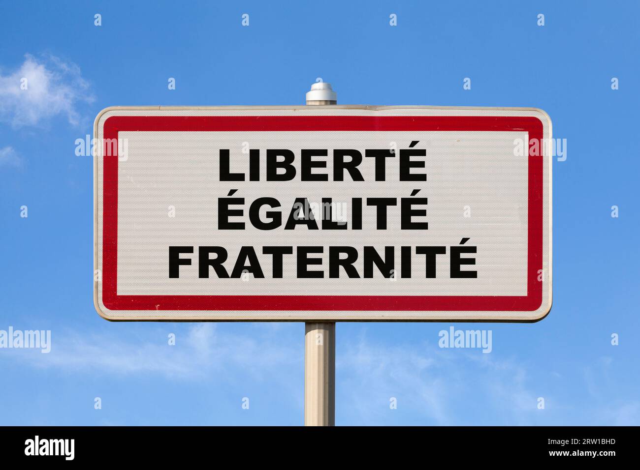 Ein französisches Ortsschild vor blauem Himmel mit der Aufschrift "Liberté, Egalité, Fraternité" in der Mitte, was auf Englisch "Liberty, Equality, Stockfoto
