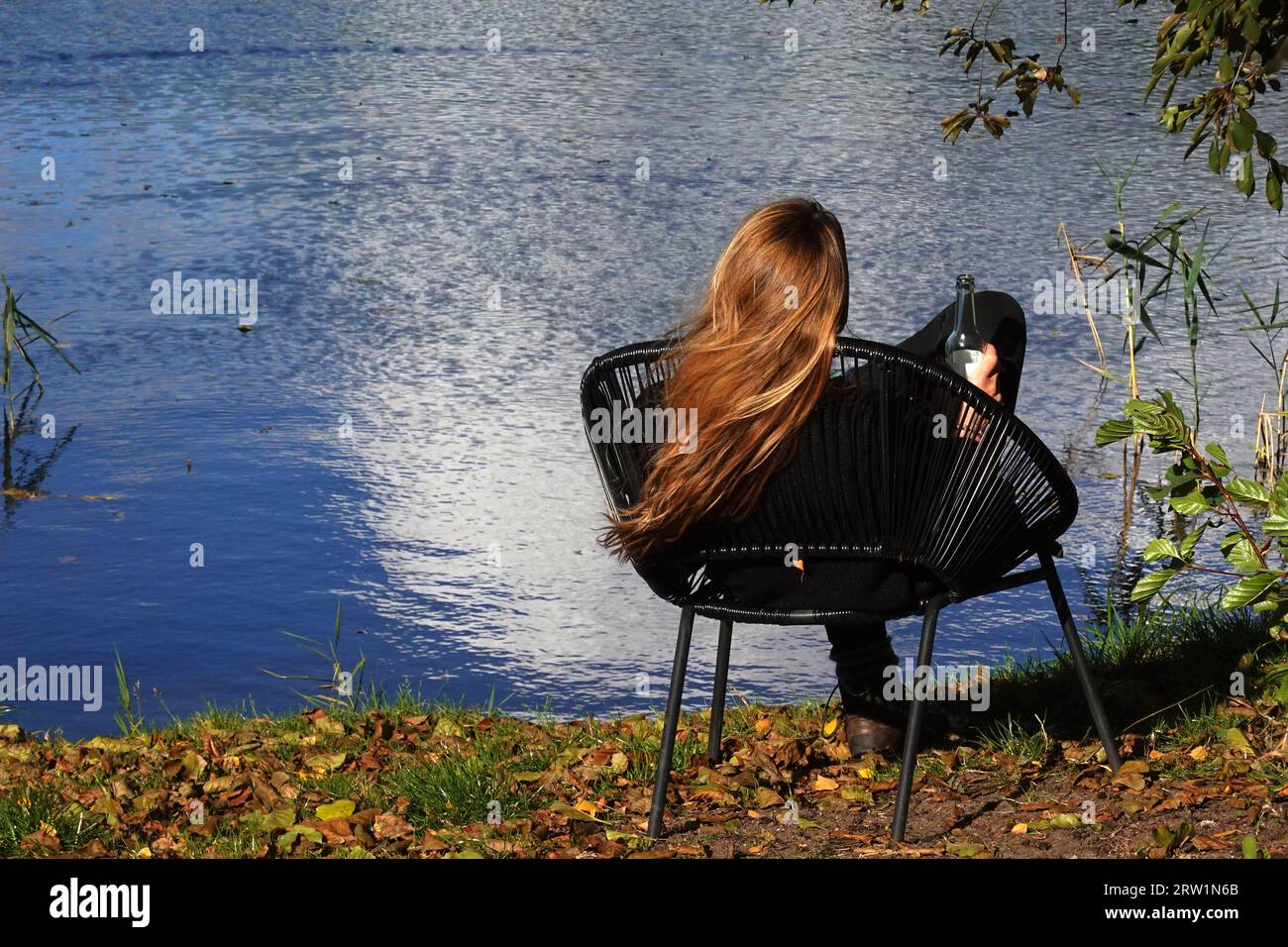 16.10.2022, Deutschland, Brandenburg, Dranse - Frau sitzt auf einem Stuhl am See. 00S221016D127CAROEX.JPG [MODELLVERSION: JA, EIGENSCHAFTSVERSION: NEIN (C) C Stockfoto