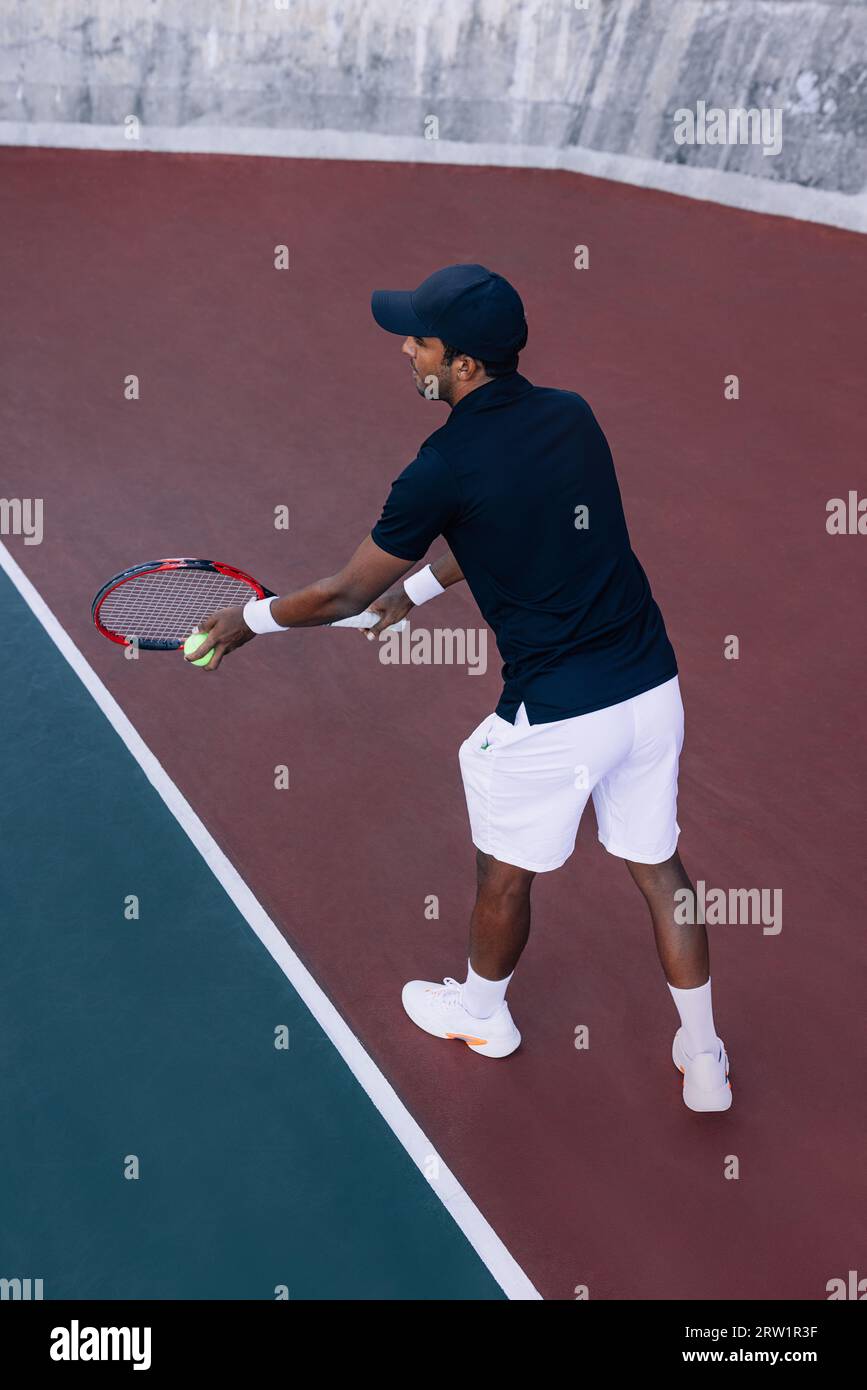 Tennisspieler mit einem Schläger, der bereit ist, einen Tennisball zu servieren, der an der Baseline steht Stockfoto