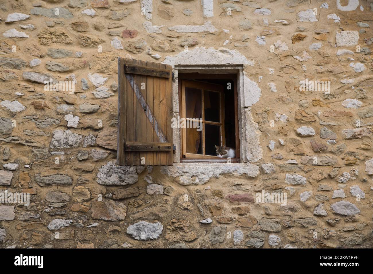 Eine Katze schaut aus dem Fenster eines alten Steinhauses Stockfoto