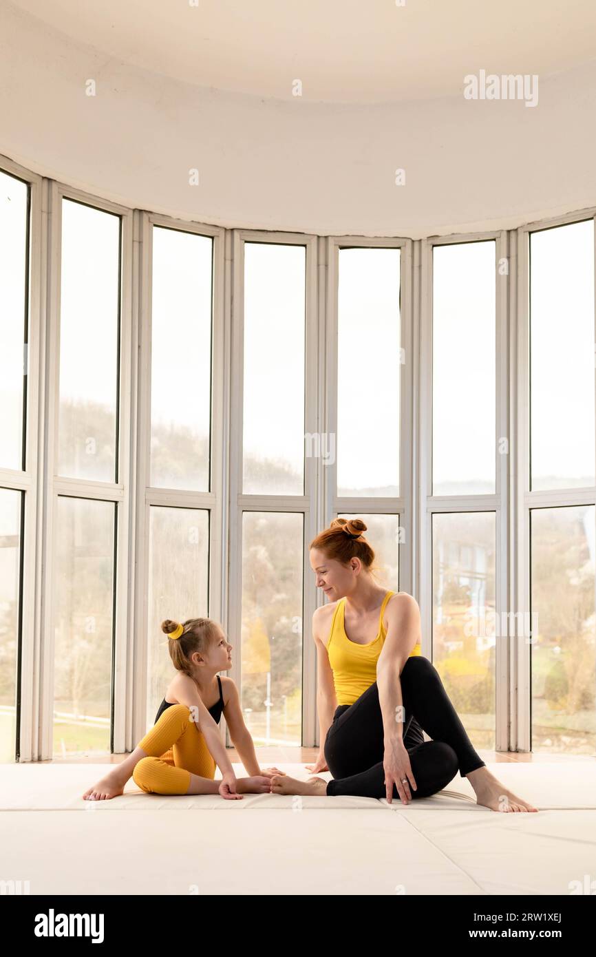 Junge Mutter und Tochter, die gemeinsam im Fitnessstudio trainieren Stockfoto