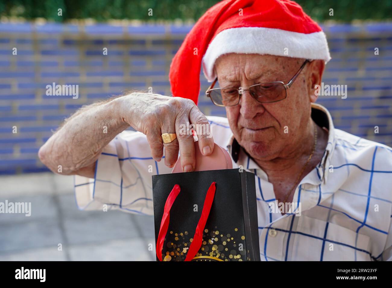 Ältere Menschen im Xmas. Überraschter reifer Mann, der weihnachtsgeschenk sieht. Ältere Menschen feiern die Krippe im Sommer Stockfoto