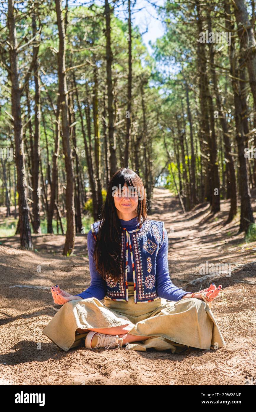 Porträt einer erwachsenen Frau mit geschlossenen Augen während der Meditation im Wald. Vertikale Aufnahme Stockfoto