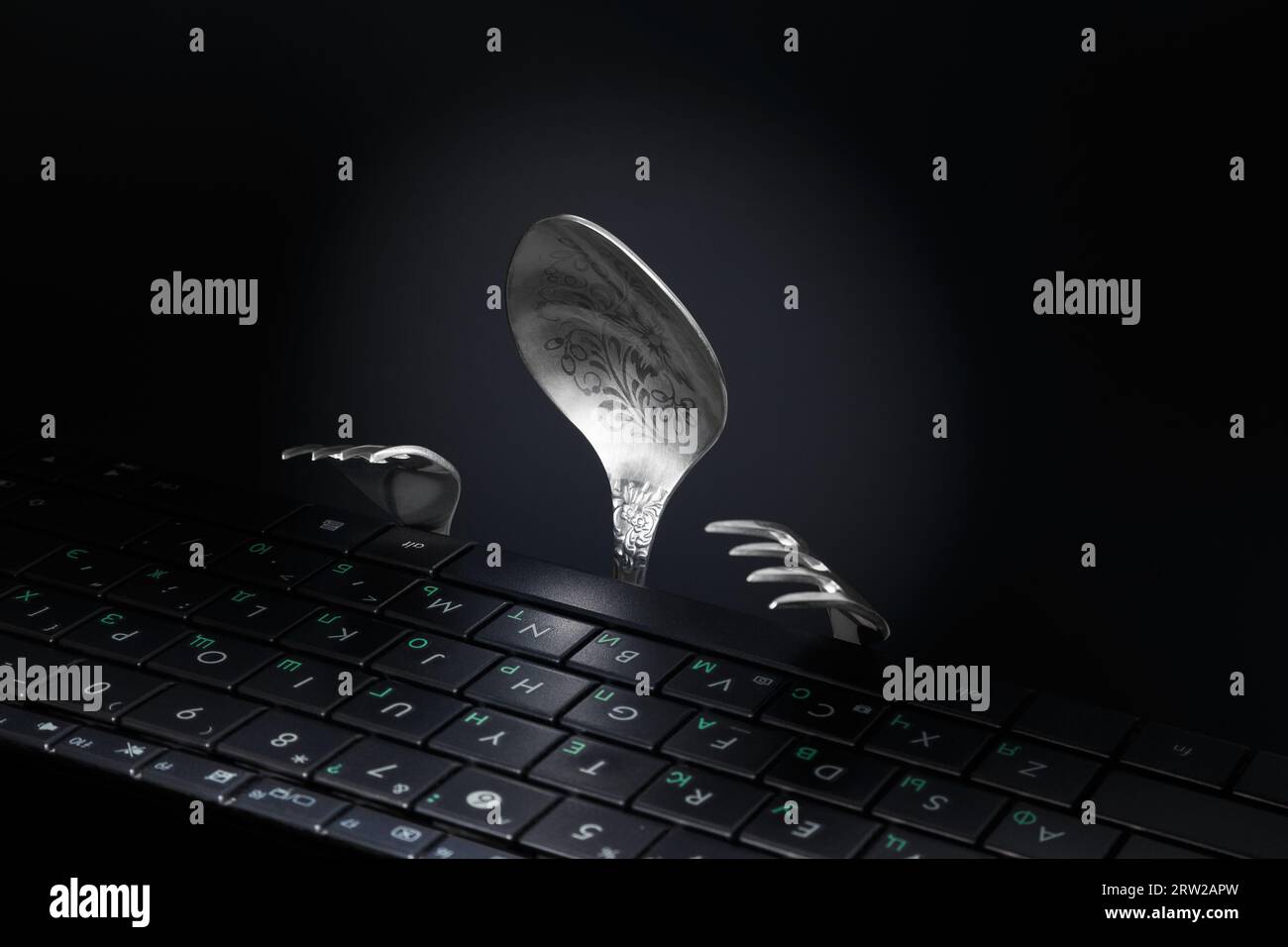 Löffel und Gabel in Form eines Mannes, der an einer Computertastatur arbeitet. Stockfoto