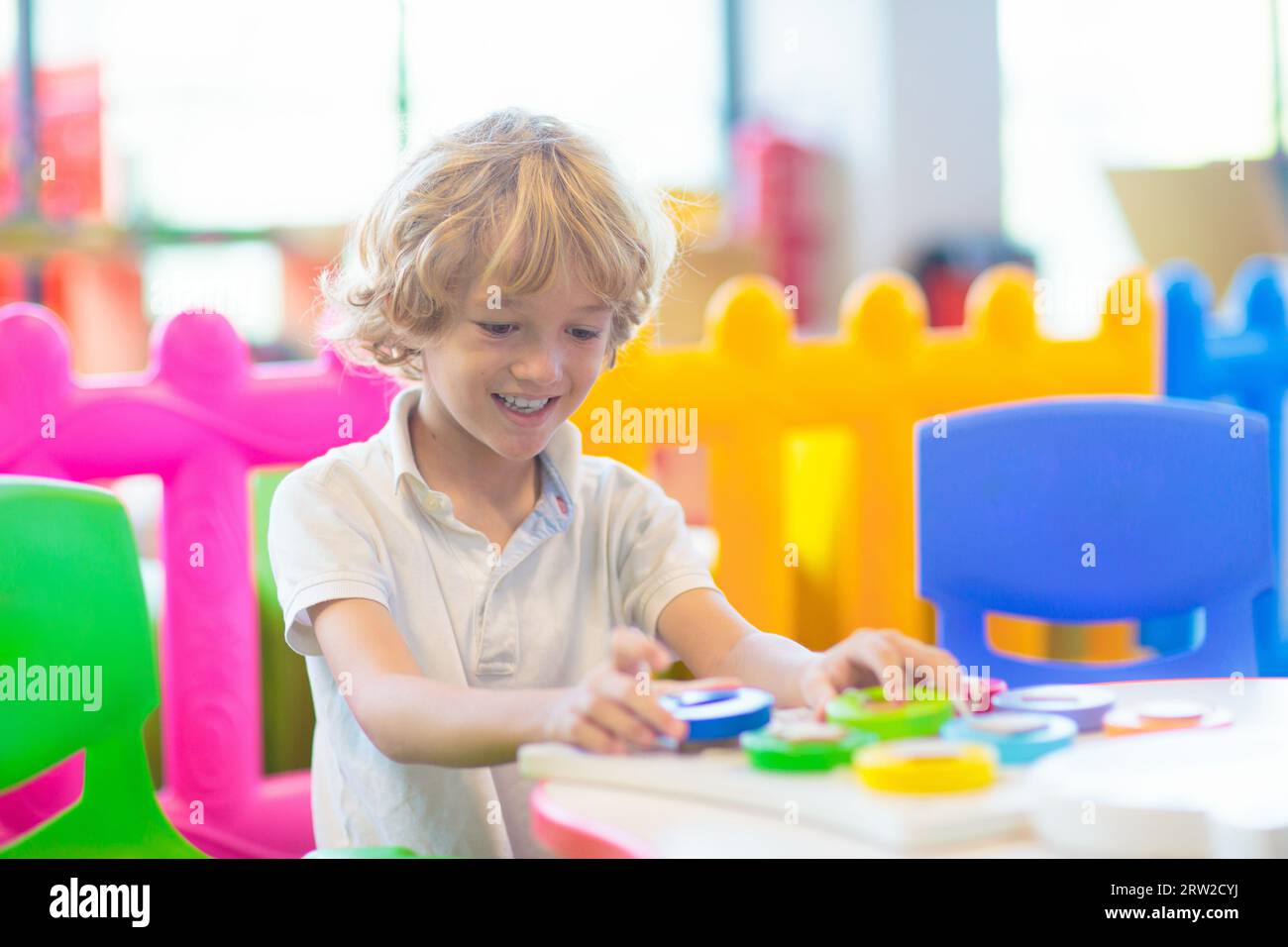 Kleiner Junge im Kindergarten oder in der Kinderbetreuung. Kinder, die im Vorschulalter mit bunten pädagogischen Spielzeugen spielen. Kinder spielen auf dem Hallenspielplatz. Stockfoto