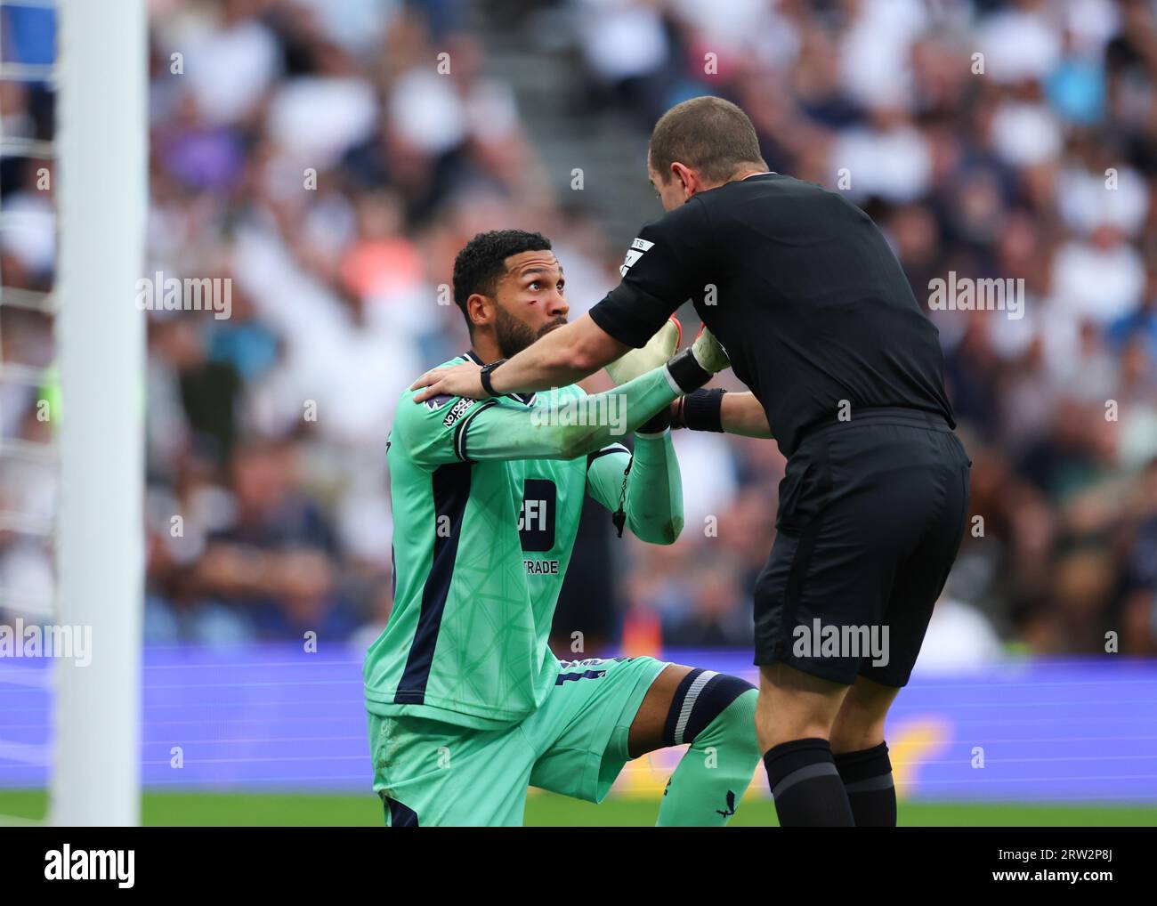 Tottenham Hotspur Stadium, London, Großbritannien. September 2023. Premier League Football, Tottenham Hotspur gegen Sheffield United; Schiedsrichter Peter Bankes weist Torhüter Wes Foderingham von Sheffield United an, vom medizinischen Personal wegen eines Schnitts auf seiner rechten Wangenknoche betrachtet zu werden Credit: Action Plus Sports/Alamy Live News Stockfoto