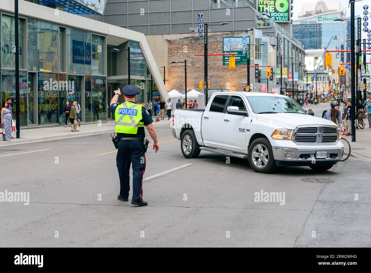 Ein Polizeibeamter aus Toronto weicht in der Yonge Street von einem Auto ab. Die Verkehrsader ist geschlossen, um die Filmaufnahmen zu erleichtern. Stockfoto