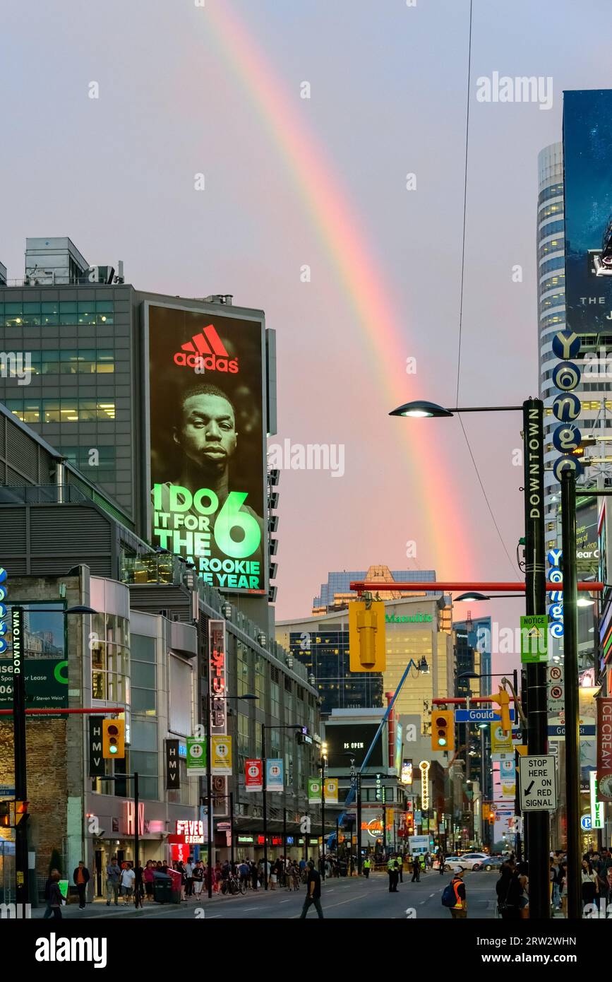 Geschlossene Yonge Street im Stadtzentrum. Ein Regenbogen erscheint am Nachmittagshimmel im Stadtzentrum. Eine Werbung für Adidas auf einem Bildschirm. Stockfoto