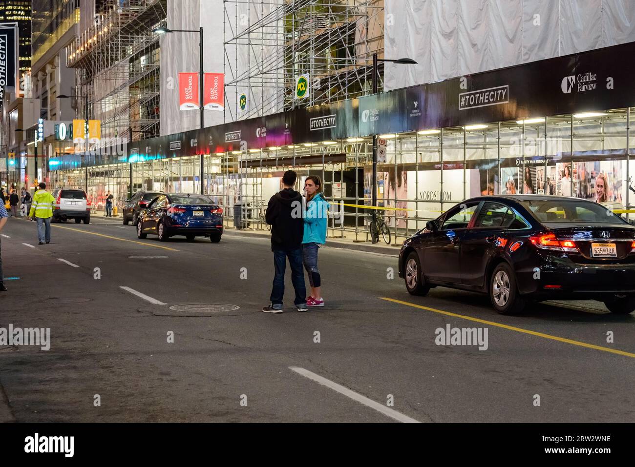 Die Mitglieder der Filmcrew stehen auf der Yonge Street, wo verschiedene Autos stehen und warten, bis die Dreharbeiten beginnen. Stockfoto
