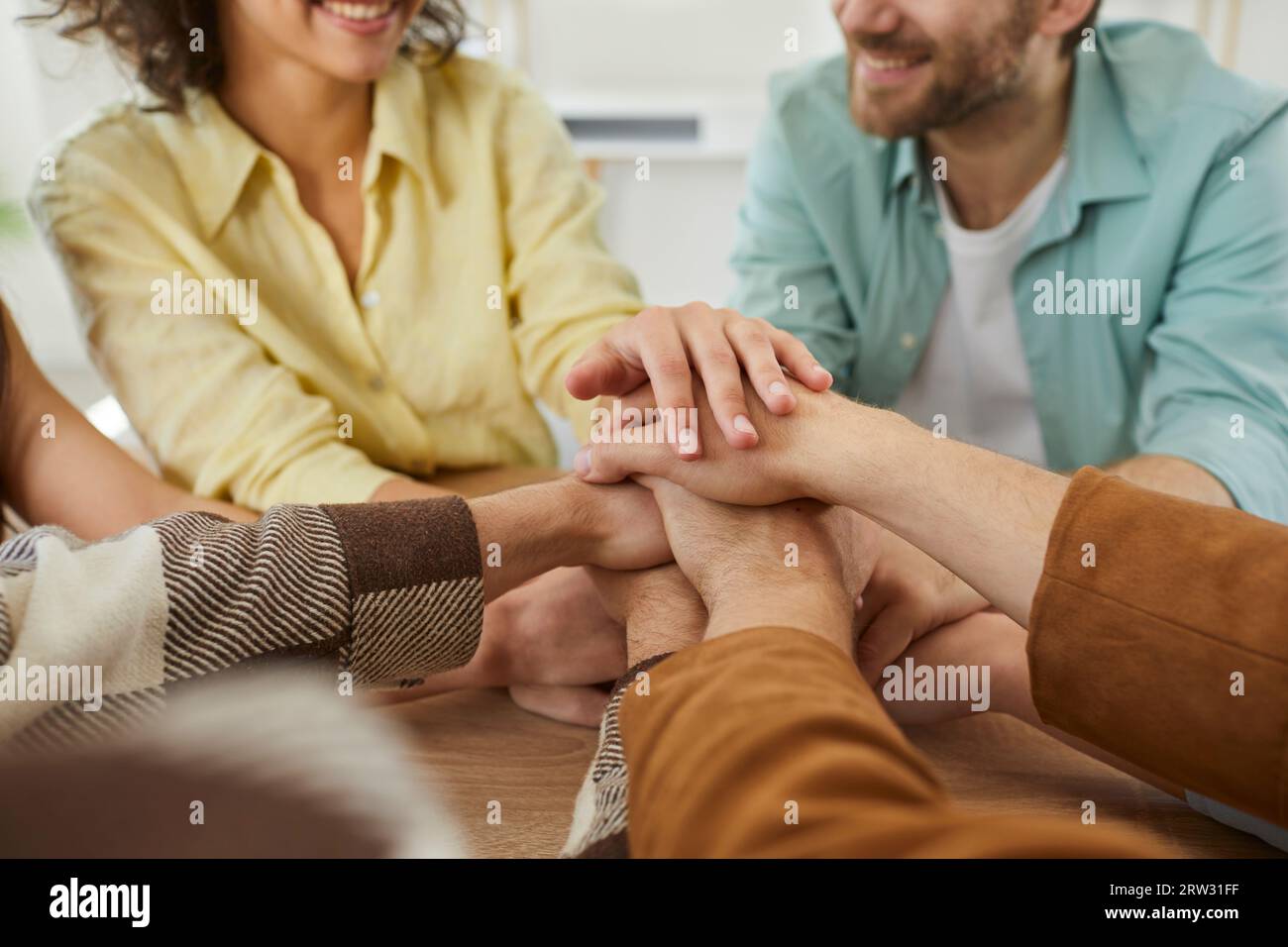 Ein Team glücklicher junger Freunde, die gemeinsam Spaß haben und ihre Hände auf einem Tisch stapeln Stockfoto