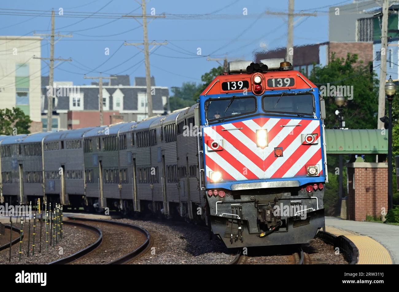 Wheaton, Illinois, USA. Ein Metra-Pendelzug auf einer Kurve, der in einem lokalen Vorortdepot ankommt, mit Pendlern, die aus Chicago zurückkehren. Stockfoto