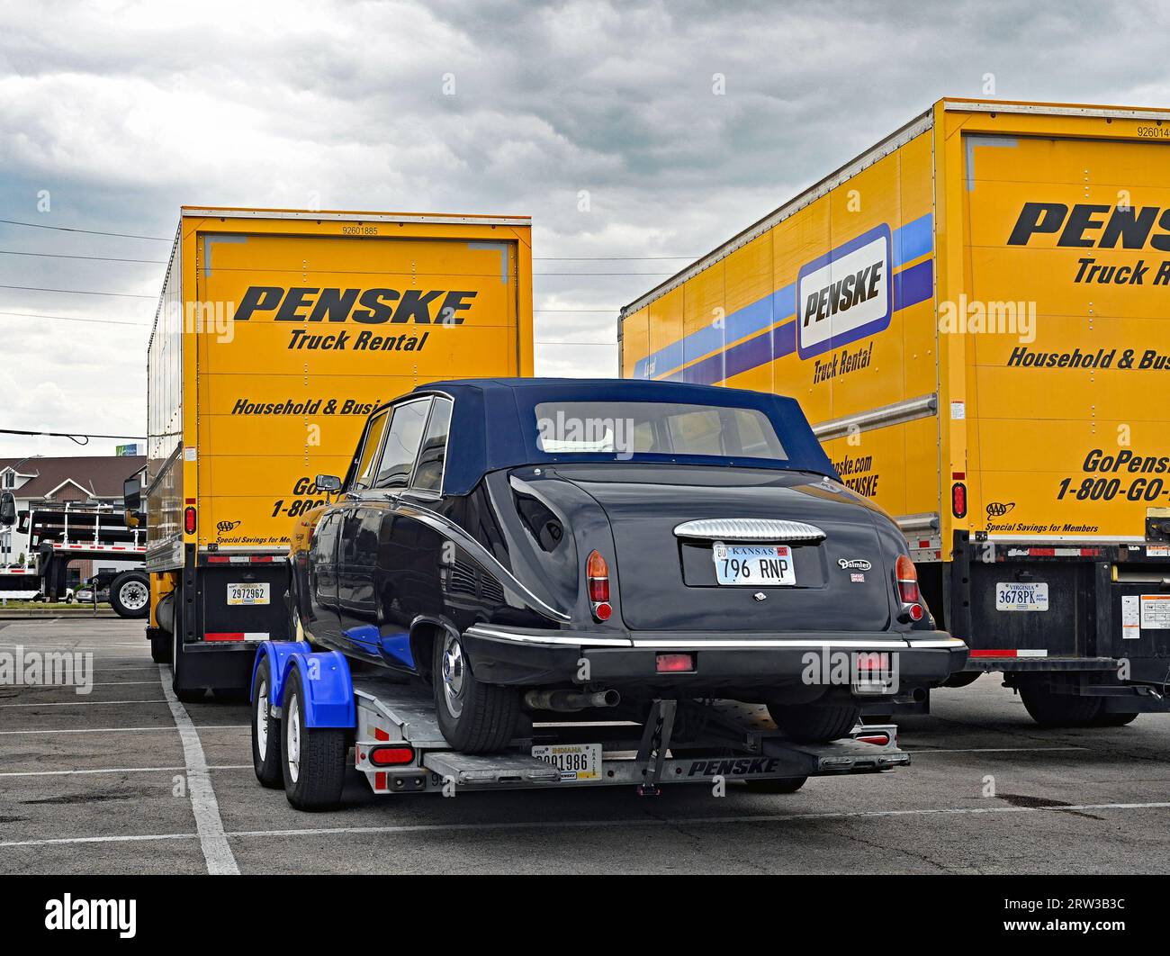 EMPORIA, KANSAS - 15. SEPTEMBER 2023 Ein Mercedes-Benz von Daimler wird auf einem Autotransporter gesichert, der hinter einem Penske-Mietwagen beladen ist Stockfoto
