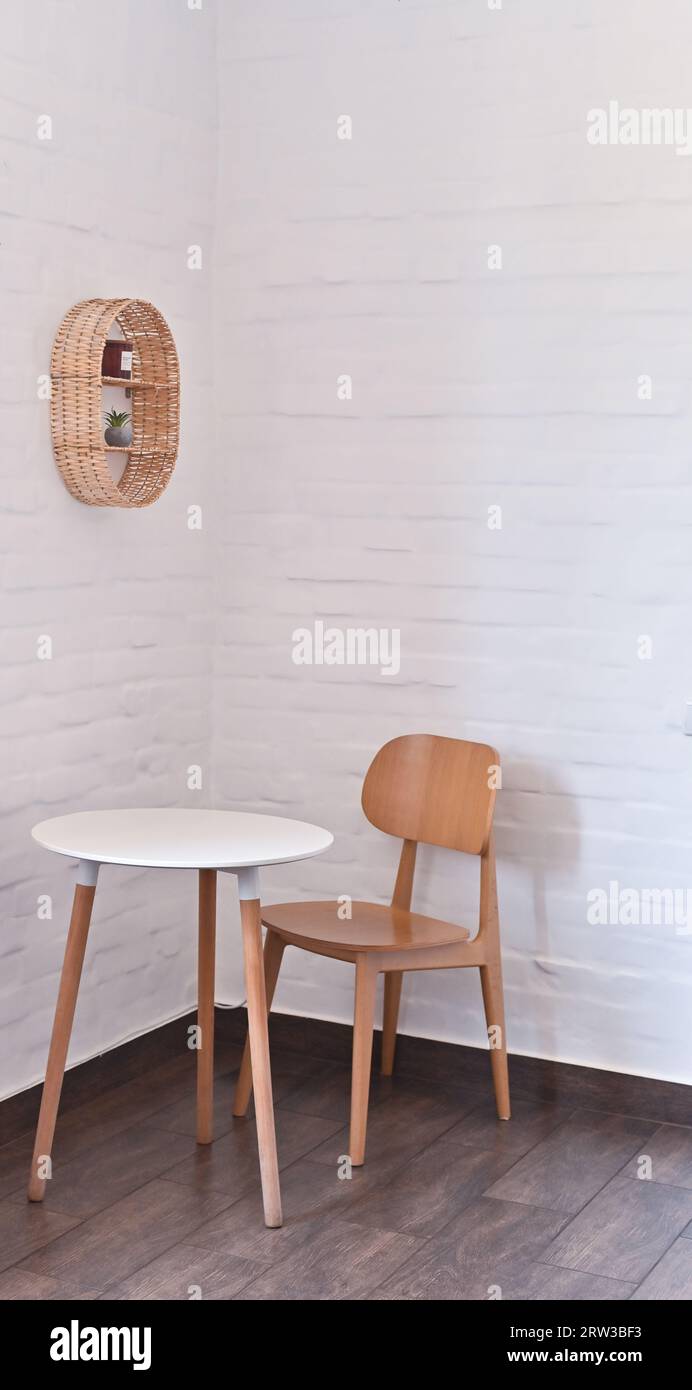 Ein Tisch und ein Stuhl in der Ecke des Zimmers. Vor dem Hintergrund einer weißen Ziegelwand. Stockfoto
