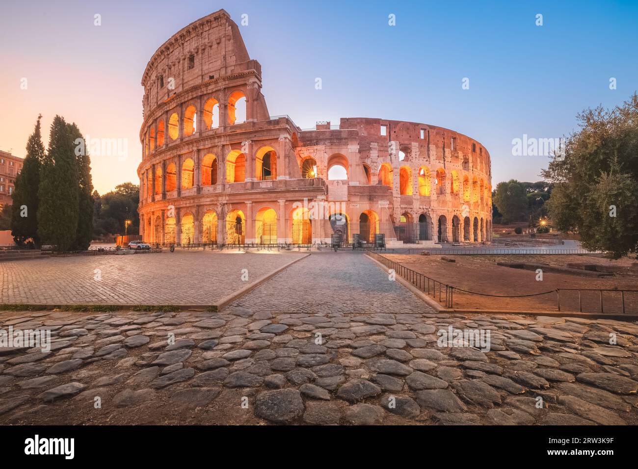 Das legendäre Flavische Amphitheater, das antike römische Kolosseum, ein berühmtes touristisches Wahrzeichen, das in der Dämmerung und bei Sonnenaufgang im historischen Rom, Italien, erleuchtet wird. Stockfoto