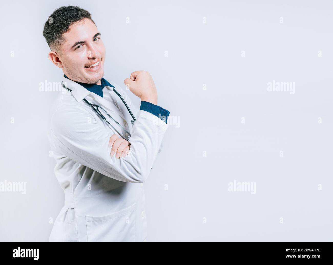 Arzt zeigt Muskeln und lächelt isoliert. Junger Arzt, der Kraft mit seinem Arm zeigt Stockfoto