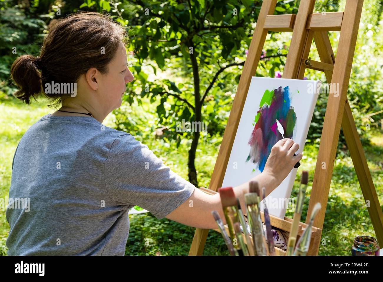 Frau malt mit Palettenmesser in einem Garten, Frau malt mit Palettenmesser in einem Garten Stockfoto