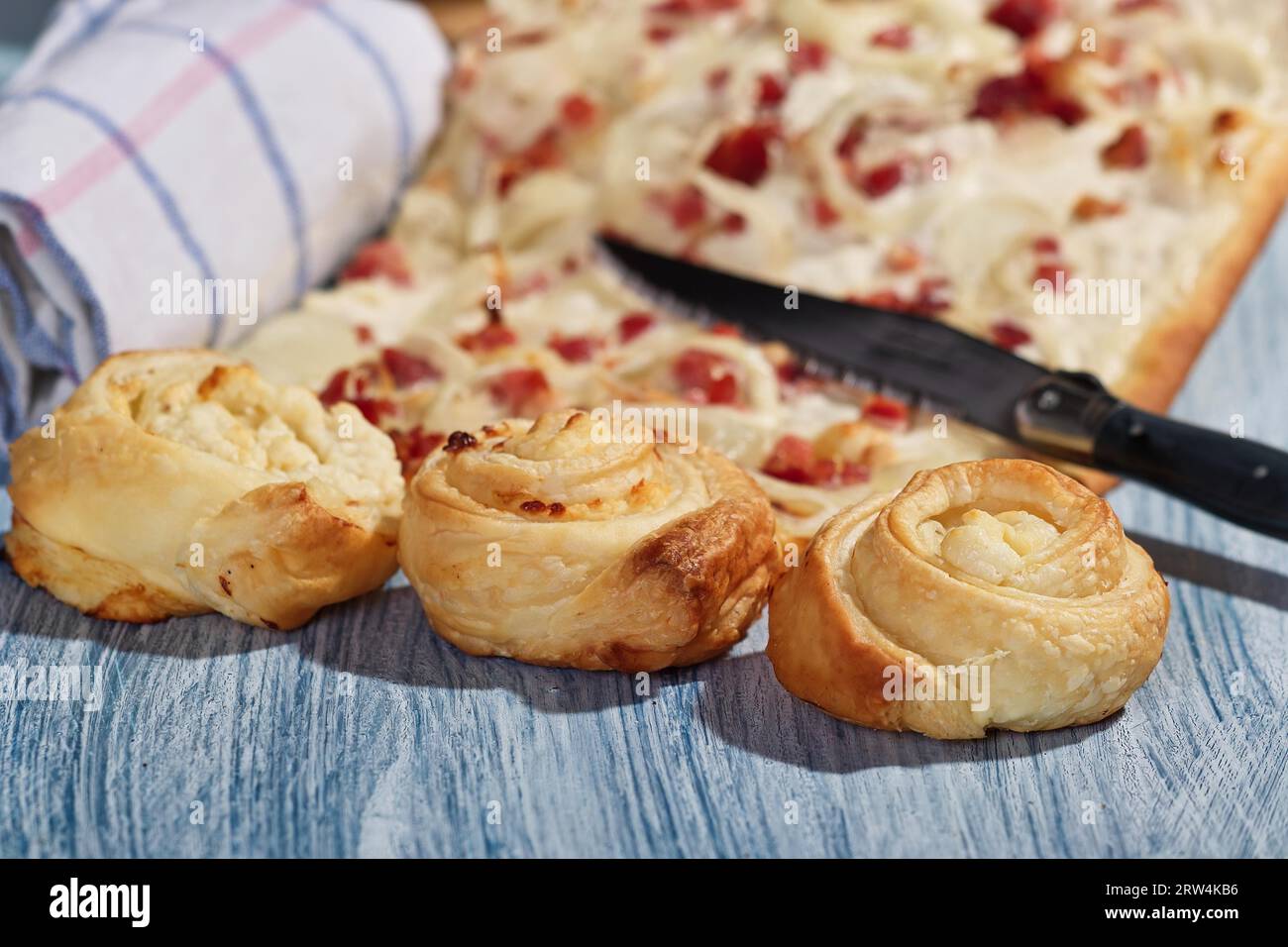 Flammkuchen und drei Blätterteigkuchen auf rustikalem Boden Stockfoto