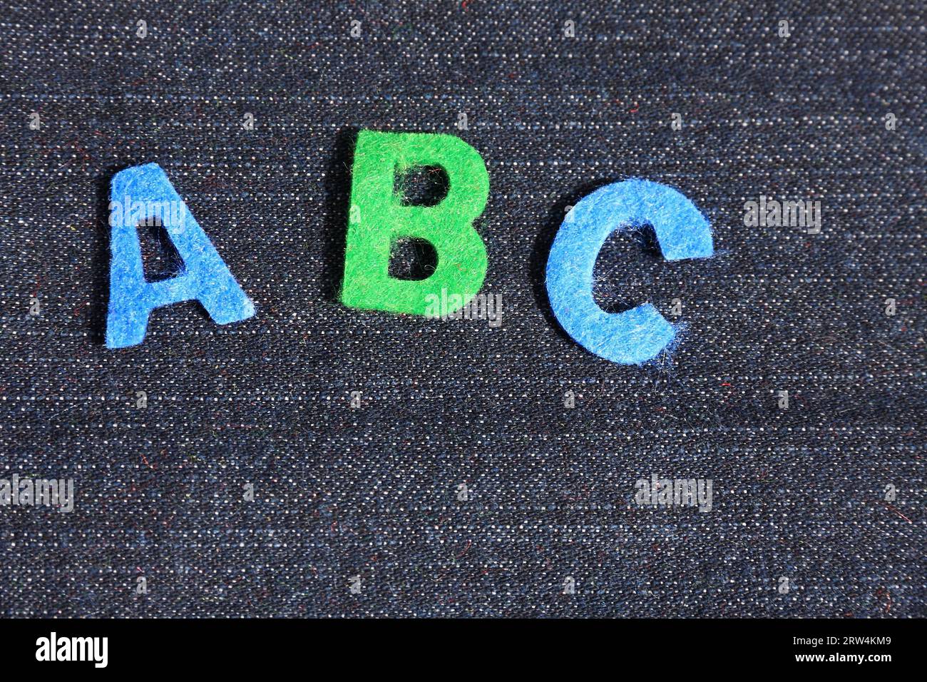 Die Buchstaben A, B und C in blau und grün, Hintergrund dunkler Denim Stockfoto