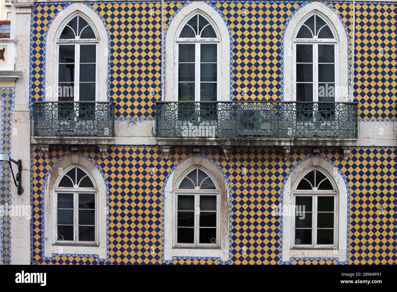 Traditionelles portugiesisches Gebäude mit blau und gelb karierter Fassade und Bogenfenstern in Lissabon, Portugal Stockfoto