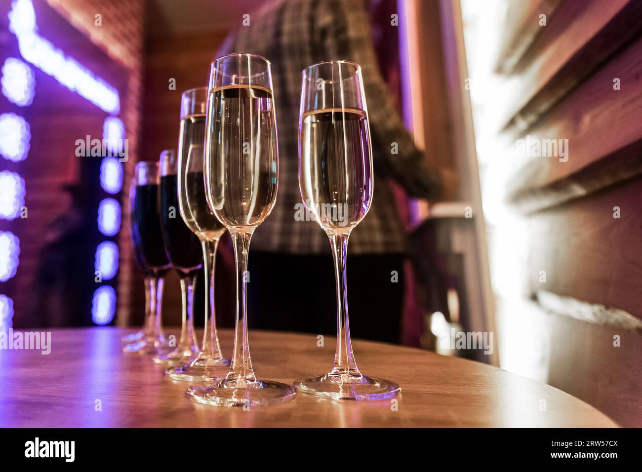 Gekühlter Champagner oder weißer Sekt, Alkohol im Glas, Rotwein auf dem Tisch ein verschwommener Hintergrund des Innenraums. Stockfoto