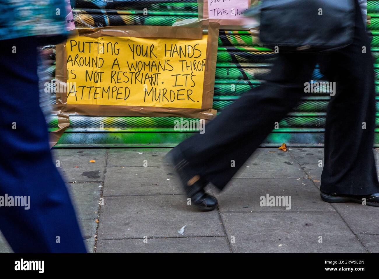 London, Großbritannien. September 2023. Ein Mann geht während der Demonstration an Schildern und Botschaften in Peckham Hair and Cosmetics auf der Rye Lane vorbei. Demonstratoren versammelten sich vor dem Peckham Hair and Cosmetics Shop über ein Video, das in den sozialen Medien zirkulierte. Das Video zeigt einen Streit zwischen einer Frau und dem männlichen Besitzer von Peckham Hair and Cosmetics, Sohail Sindho, 45, der während der Auseinandersetzung seine Hände um ihre Kehle zu legen scheint. Quelle: SOPA Images Limited/Alamy Live News Stockfoto