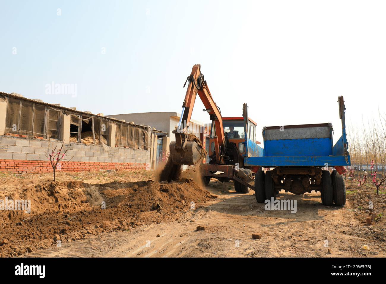 LUANNAN COUNTY, China - 15. April 2021: Bauern nutzen Bagger, um das Land zu ebnen und grüne Setzlinge auf dem Land zu Pflanzen Stockfoto