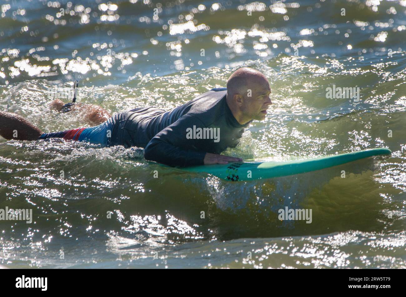 Cape May, Usa. September 2023. Surfer versuchen, einige Wellen zu reiten, die Überreste des Hurrikans Lee sind, während die Leute das warme Wetter am Samstag, den 16. September 2023 am Cove Beach in Cape May, New Jersey genossen. Die Temperaturen lagen am letzten Wochenende vor Herbst in den 80er Jahren. William Thomas Cain/Alamy Live News Stockfoto