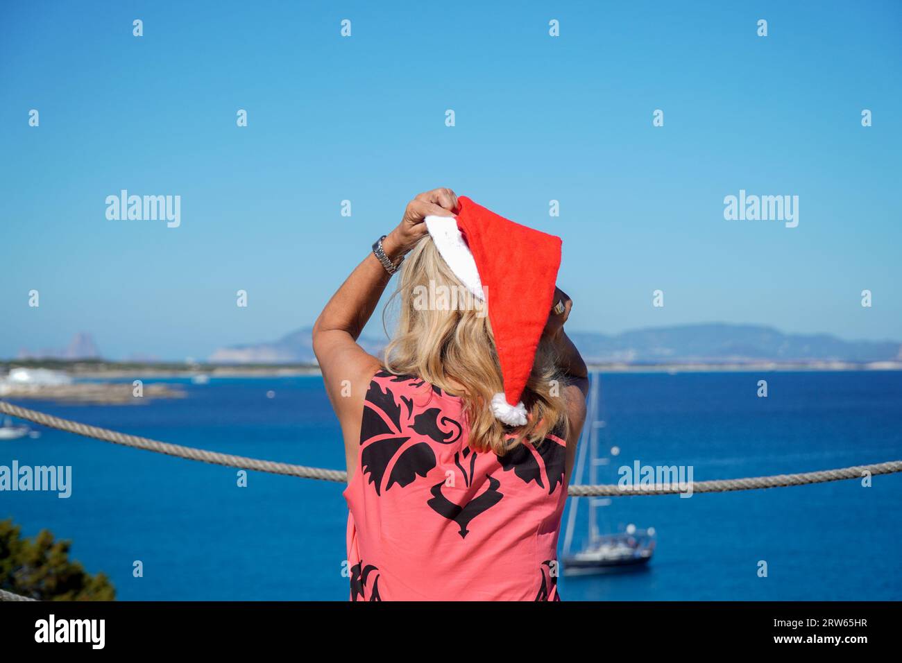 Erwachsene Frau mit weihnachtsmannhut in einem Hotel zu weihnachten. Weihnachtsfeiern in den Sommerferien im Dezember. Stockfoto