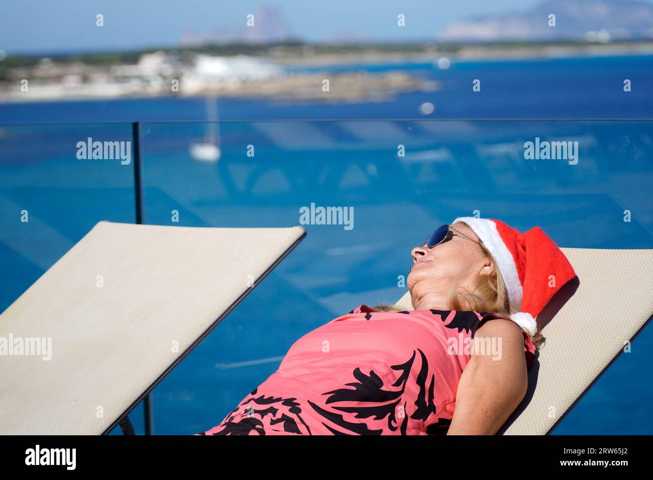 Reife Frau mit weihnachtsmannhut in einem Sommerresort im dezember. weihnachten im Urlaub feiern. Stockfoto