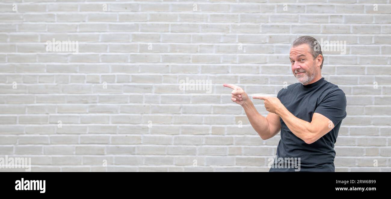 Werbefoto eines attraktiven freundlichen Mannes, der auf die linke Seite zeigt und auf die Kamera schaut Stockfoto