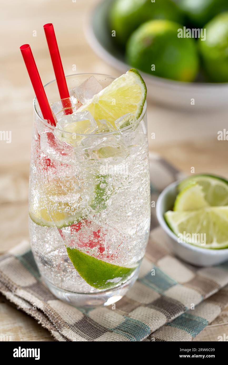 Ein Glas kaltes Mineralwasser mit Kalkspalten auf einem Holztisch Stockfoto