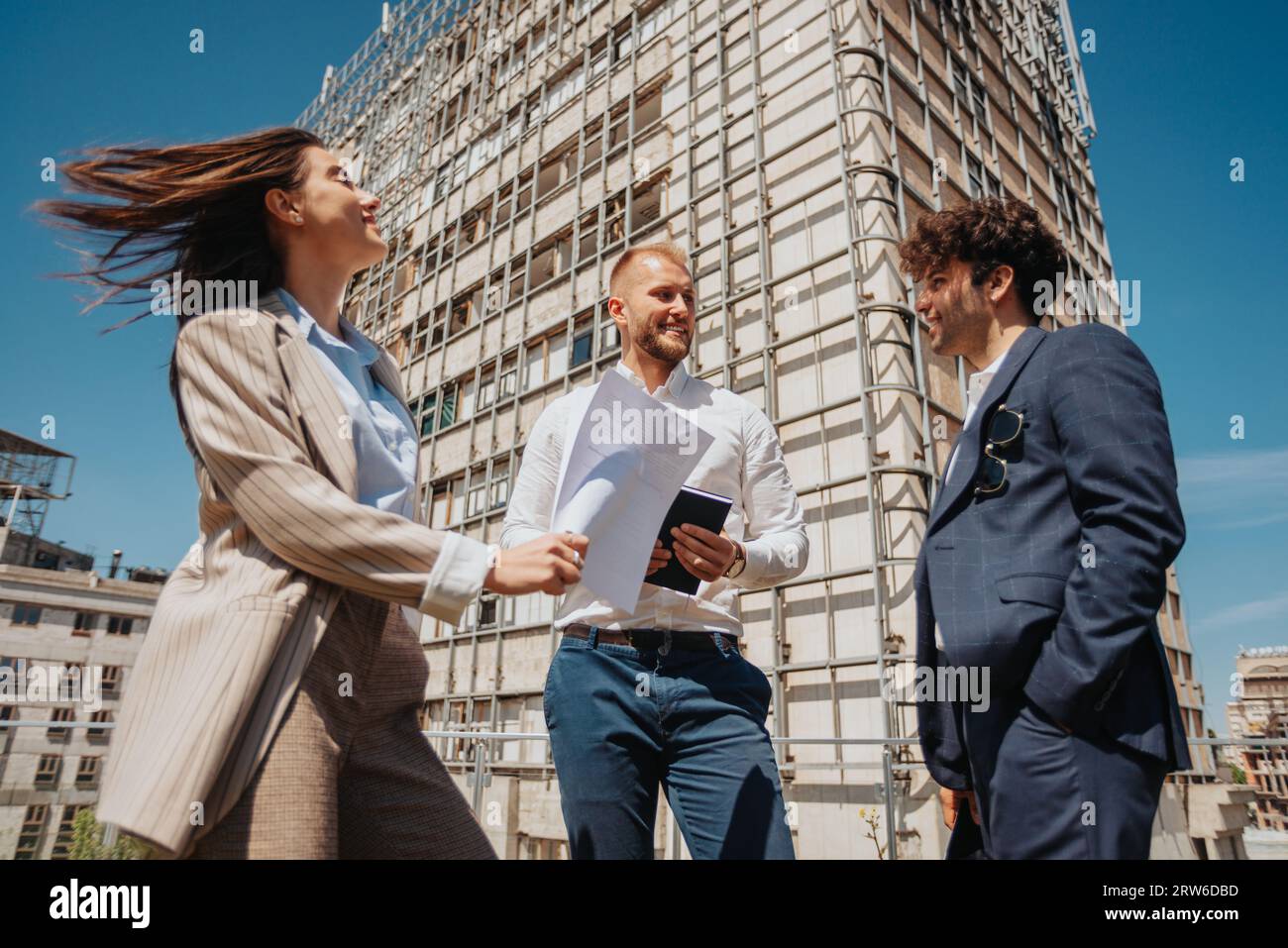 Glückliche, erfolgreiche Architekten arbeiten in einer positiven Atmosphäre in der Stadt zusammen, an einem schönen sonnigen Tag. Stockfoto