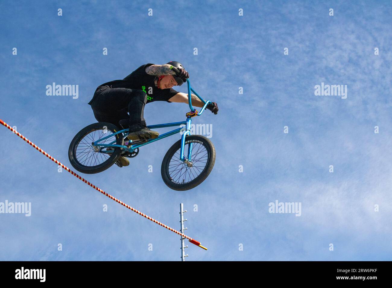 Details eines Airborne BMX Riders in Mid Air gegen einen blauen Himmel, als er einen Hochsprung bei einem aufregenden Wettbewerb auf einem Sommerfestival löst. Stockfoto