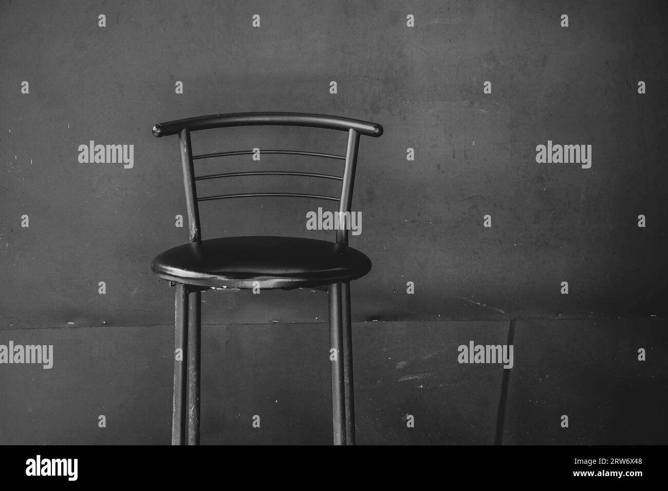 Ein alter schäbiger Stuhl steht vor dem Hintergrund einer schwarzen Wand aus Nahaufnahme, Möbel und Design Stockfoto