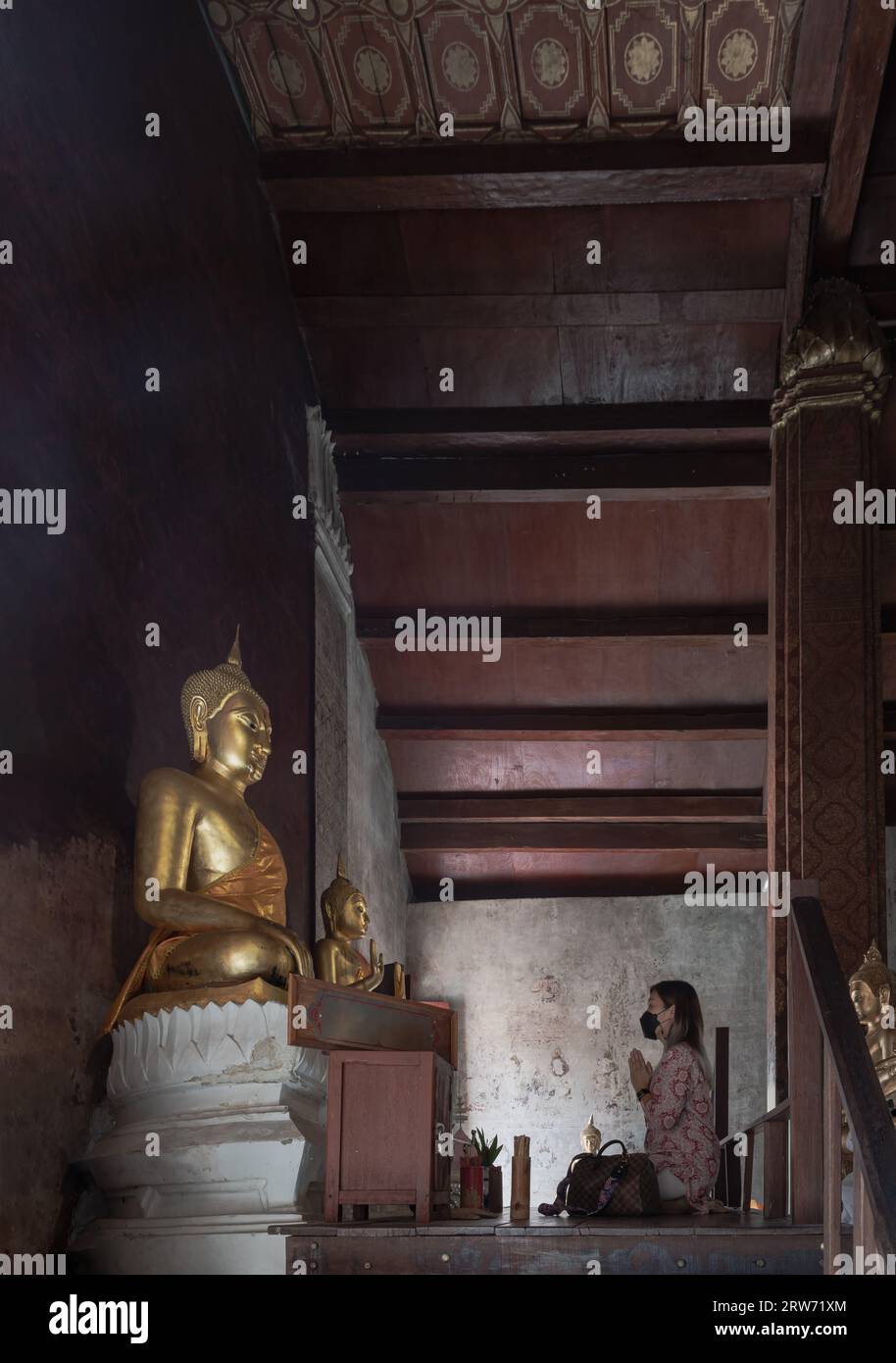 Phetchaburi, Thailand - 14. Mai 2022 : Junge Frau, die sitzt, zollt Phra Phuttha Chinnarat in der Kapelle des Wat yai Suwannaram-Tempels Respekt. Anbetung p Stockfoto