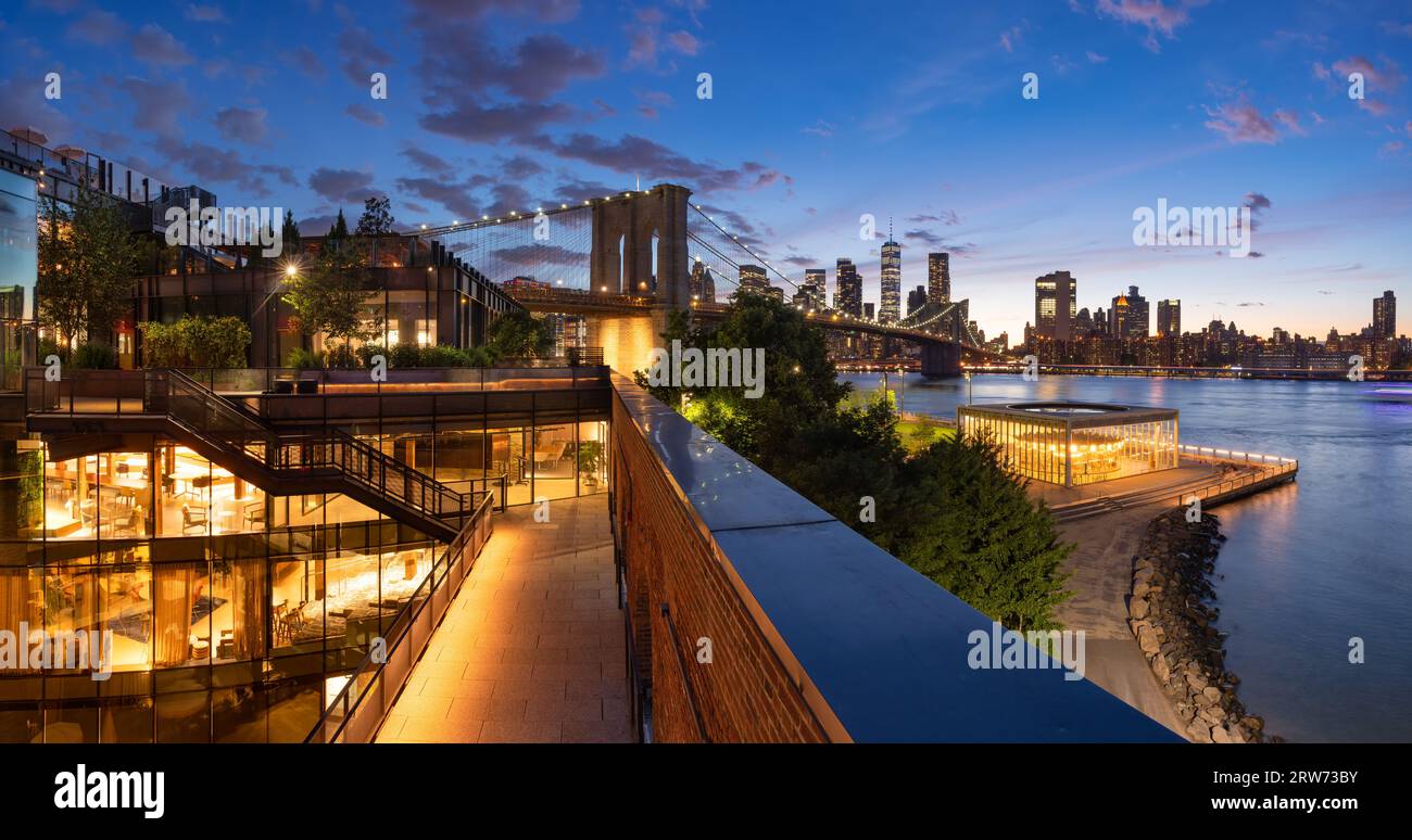 Abendlicher Blick auf die Brooklyn Bridge, die Wolkenkratzer von Lower Manhattan und den Empire Fulton Ferry Park. DUMBO-Nachbarschaft, New York City Stockfoto